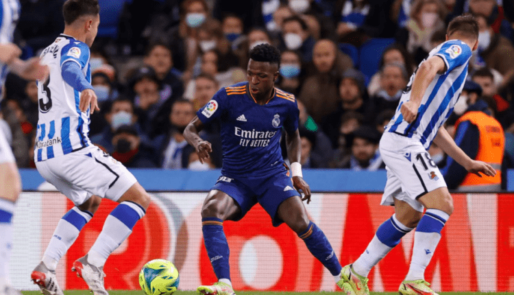 Vinícius Júnior, rodeado por Martín Zubimendi y Andoni Gorosabel en un Real Sociedad de Fútbol - Real Madrid Club de Fútbol